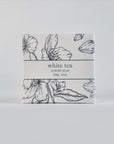 White tea luxury soap is featured in its square-shaped package with flower illustration in black and black lettering with the information.
