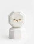 White velvet ring box with a gold heart-shaped ring with diamonds and brown gemstones on a white background.