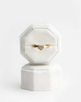 White velvet ring box with a gold heart-shaped ring with diamonds and brown gemstones on a white background.