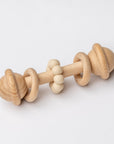 Eco-friendly wooden baby rattle with a natural maple wood ring and beige silicone teething beads, designed for infants to grasp and chew.