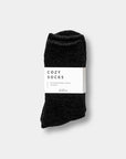 Black pair of chenille socks. Has a white band around the center that reads "Cozy Socks"