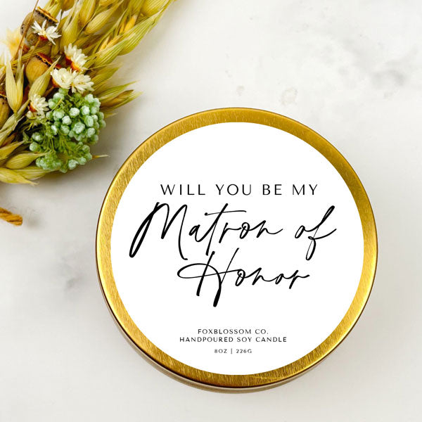 8 oz gold candle tin. Lid reads "Will you be my matron of honor" in black script