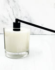 Black candle snuffer featured snuffing a white candle in a clear jar on a background.