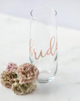 Personalized stemless glass flute with "bride" in rose gold script with roses next to it in a marble-like background.