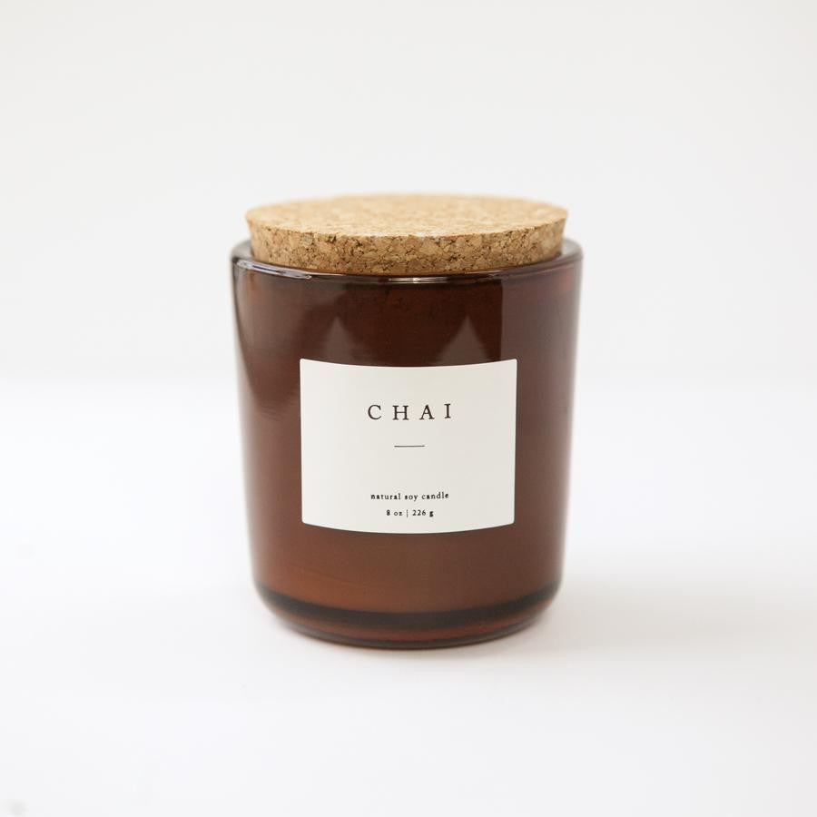 8 oz chai scented soy candle, approx 3.25" x 3.75", brown glass container with cork lid and white sticker. Pictured with dried autumn themed florals