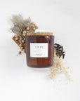 8 oz chai scented soy candle, approx 3.25" x 3.75", brown glass container with cork lid and white sticker. Pictured with dried autumn themed florals