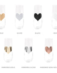 Seven stemless flute glasses with hearts displaying the sample colors of gold, silver, black, white, mirrored gold, mirrored silver and mirrored rose gold.