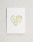 A simple yet elegant card, featuring a heart-shaped floral design rendered in gold foil, centered on a crisp white background.