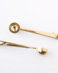 Stainless steel gold coffee scoop two of them in different positions.