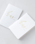 His and his vow books, white linen cover, metallic gold foil stamping, rounded corners, saddle stitch binding, featured on a white background.