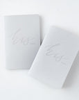 His and his gray linen letterpressed vow books, featured in a white background