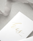 His foil stamped white vow book featured in a gray background.