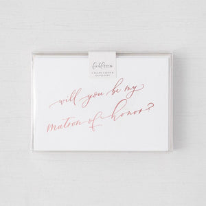 White envelope size card (approx. 3.5" x 5"), reads, "Will you be my maid of honor?" in rose gold text in a clear plastic bag. 