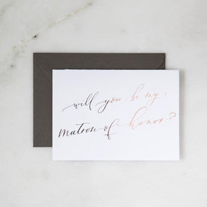 White envelope size card (approx. 3.5" x 5"), reads, "Will you be my maid of honor?" in rose gold text with slate gray envelope color option.
