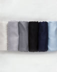 Display of 6 pashminas. White, light grey, ash grey, black, newport navy and light blue.