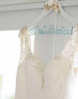 Wedding dress hanging on a white seashell and starfish hanger with ice blue aluminum wire, handcrafted name. " Mrs.DeBartolo" and heart shapes at the beginning and end.