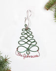 Personalized Christmas Tree Ornament — Christmas tree outline-shaped ornament crafted from green aluminum wire and personalized in red aluminum wire with The Johnsons and decorated with tree branches in each corner on a white background.