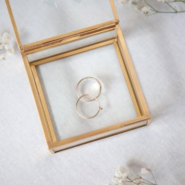 Personalized jewelry box, A gold-framed jewelery glass box opened with two gold rings inside.
