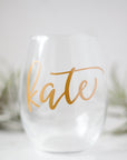 Stemless Wine Glass, shown in the image, is a transparent wine glass personalized with the name Kate with air plants in the background.