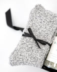 Gray 'foxblossom' socks with a black ribbon, and 'herbivore' detox soaking salts in a glass jar, placed in a small black 'foxblossom' box with a black ribbon.