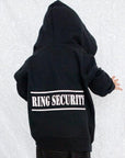 The back of a Ring Bearer Hoodie in black with the word Ring Security on the back on a white background, and a child is wearing it.