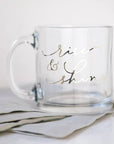 Clear coffee mug with the personalization rise & shine in silver letters with a grey linen nap in underneath.