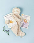 Slumberkins Slumber Sloth stuffed toy with Slumber Sloth hard book. Shown on a blue background with a floral accent. Key product in our Welcome Slumber gift box.