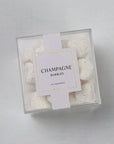 Sugarfina Champagne bubbles in their clear container showcasing the bubbles inside and the label black lettering with gold details.