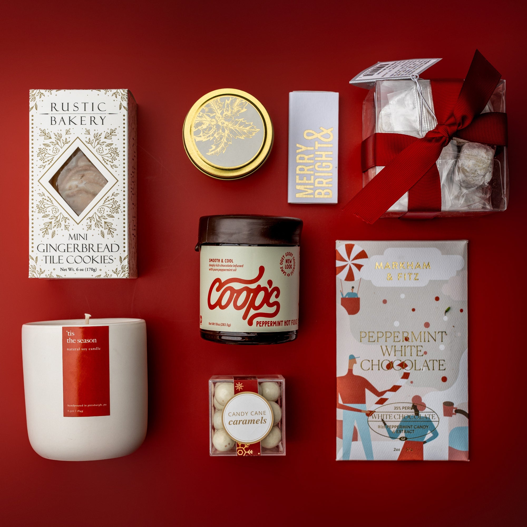 Collection of Christmas-themed products including a candle, cookies, and chocolate on a red background