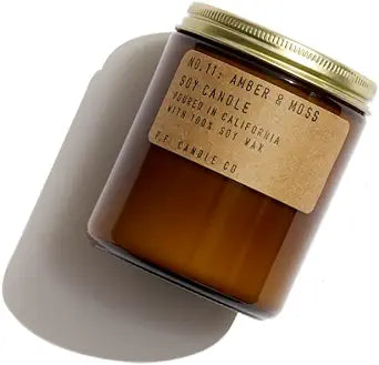 Amber & Moss by PF Candle, featuring the candle amber/ light brown jar with gold lid, with the label done in kraft light brown paper with black lettering. 