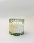 Amber & Moss Candle is featured in its  green trinket glass jar, on a white background.