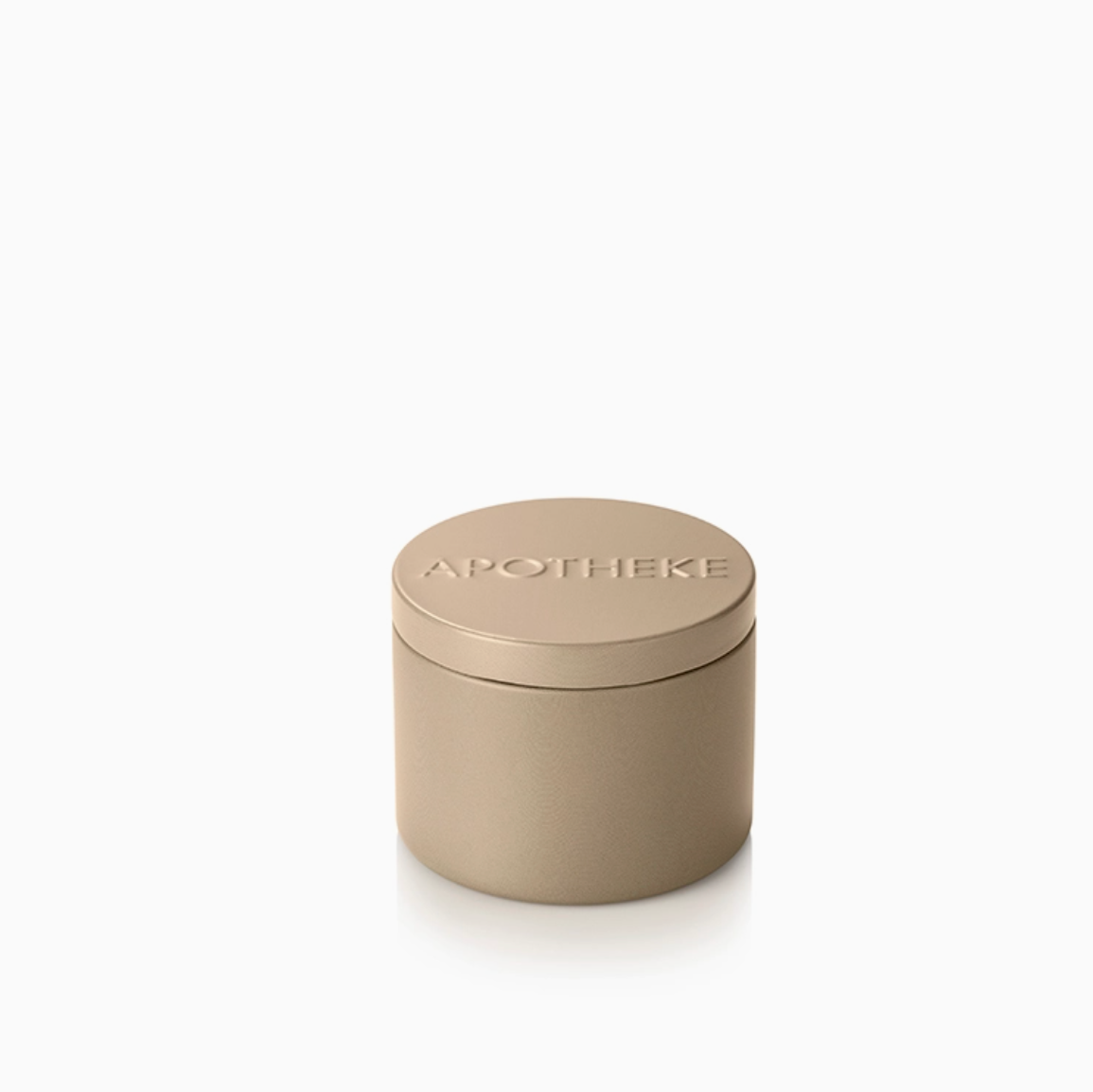 A small cylindrical metal tin with a matching lid, embossed with the brand name 'APOTHEKE', in a warm taupe-beige color, set against a clean white background.