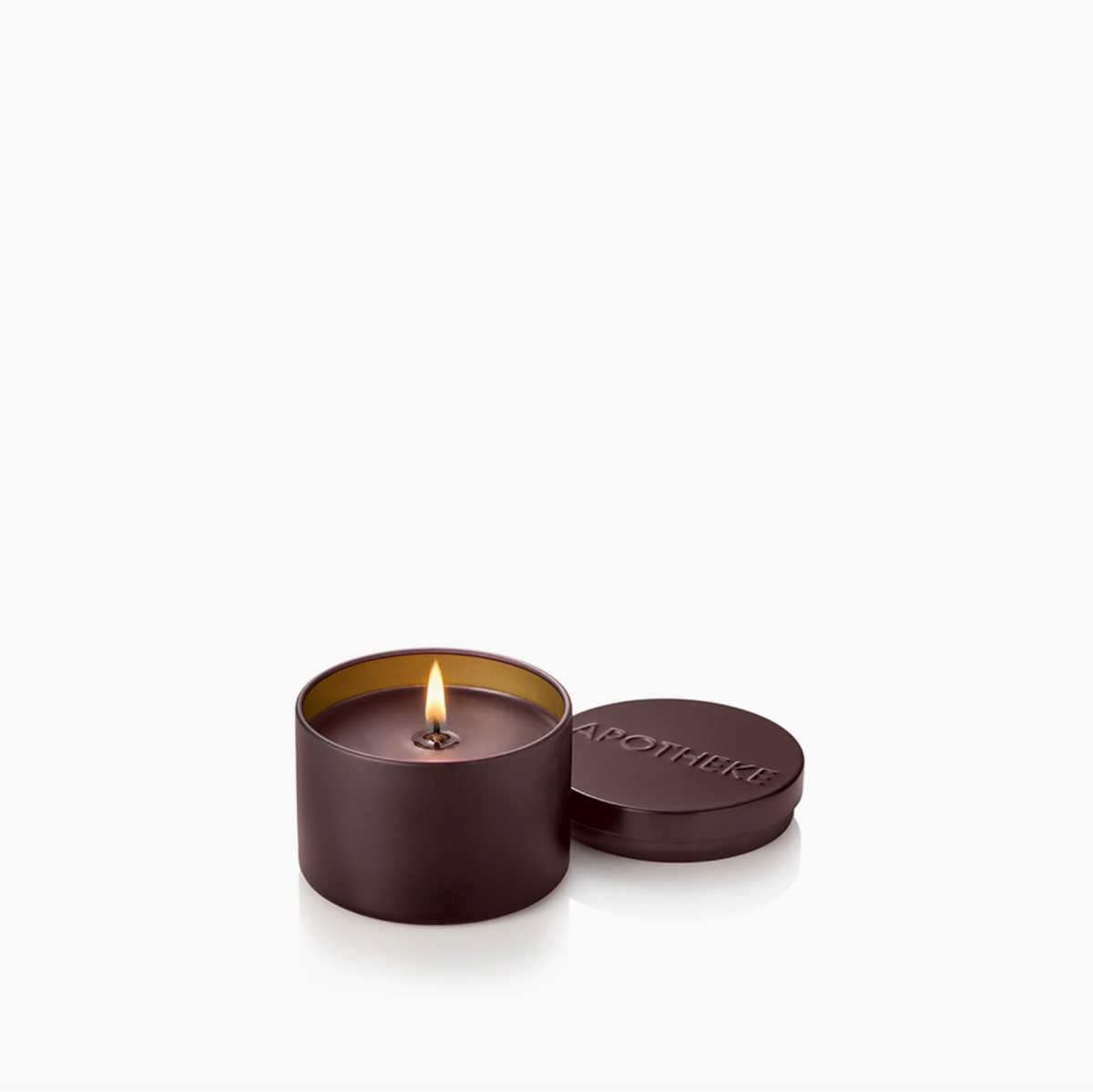 A lit cylindrical candle in a dark brown matte tin with its lid beside it, embossed with the brand name 'apotheki'.
