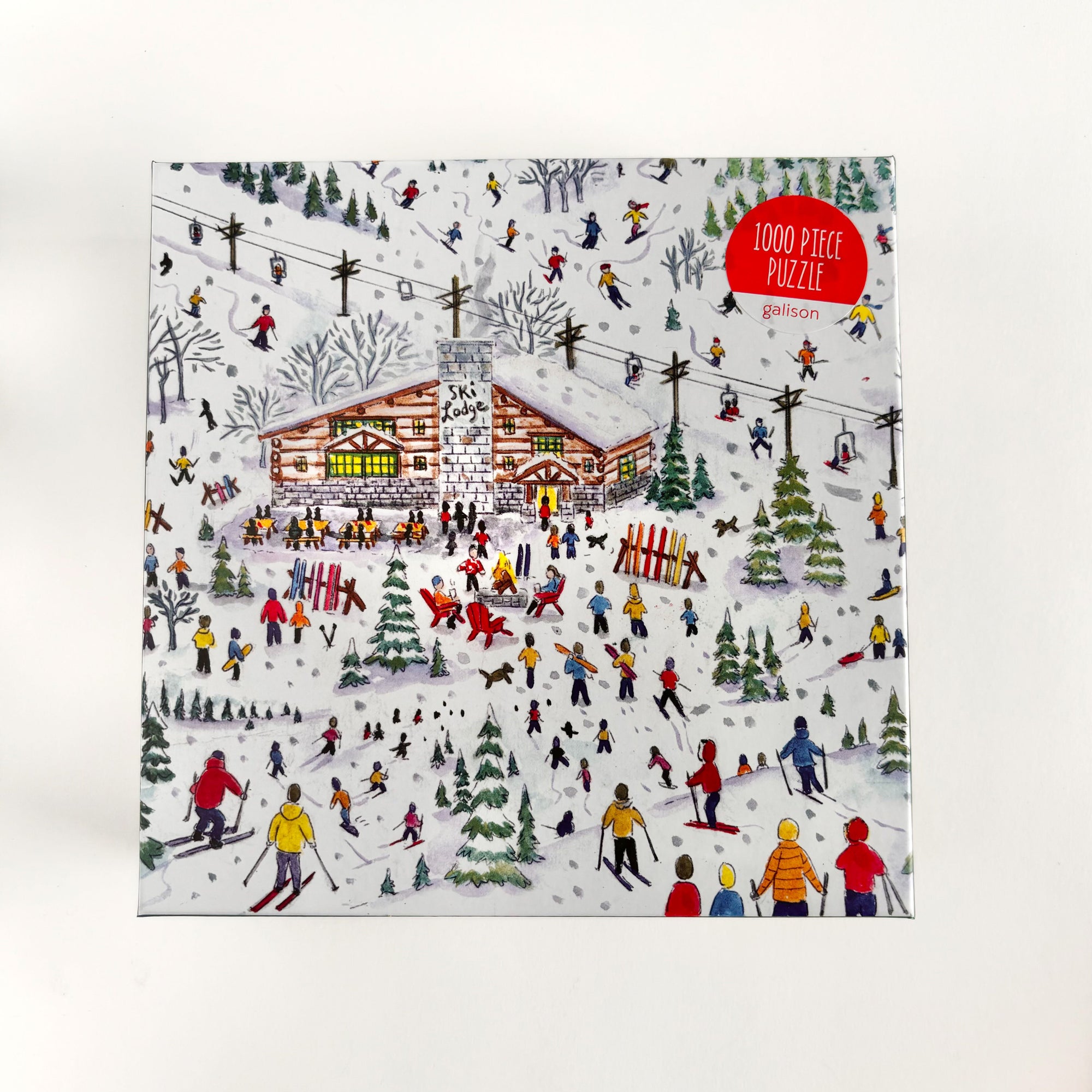 Apres Ski puzzle is featured in its box container that show the apres ski image of the puzzle with a red sticker with white lettering on a white background. 