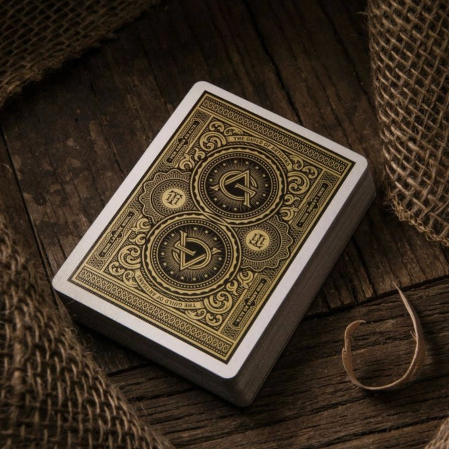 Playing card box with intricate gold design on a wooden surface
