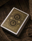 Playing card box with intricate gold design on a wooden surface