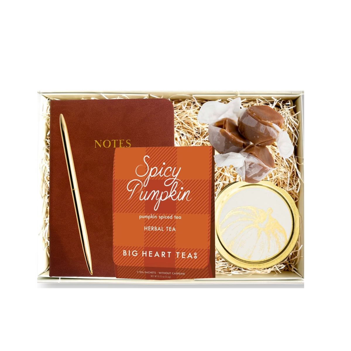 A gift box set from Big Heart Teas featuring a 'Spicy Pumpkin' herbal tea tin, a brown notebook with a gold pen, and wrapped chocolates nestled in shredded paper inside a clear-lidded gift box.