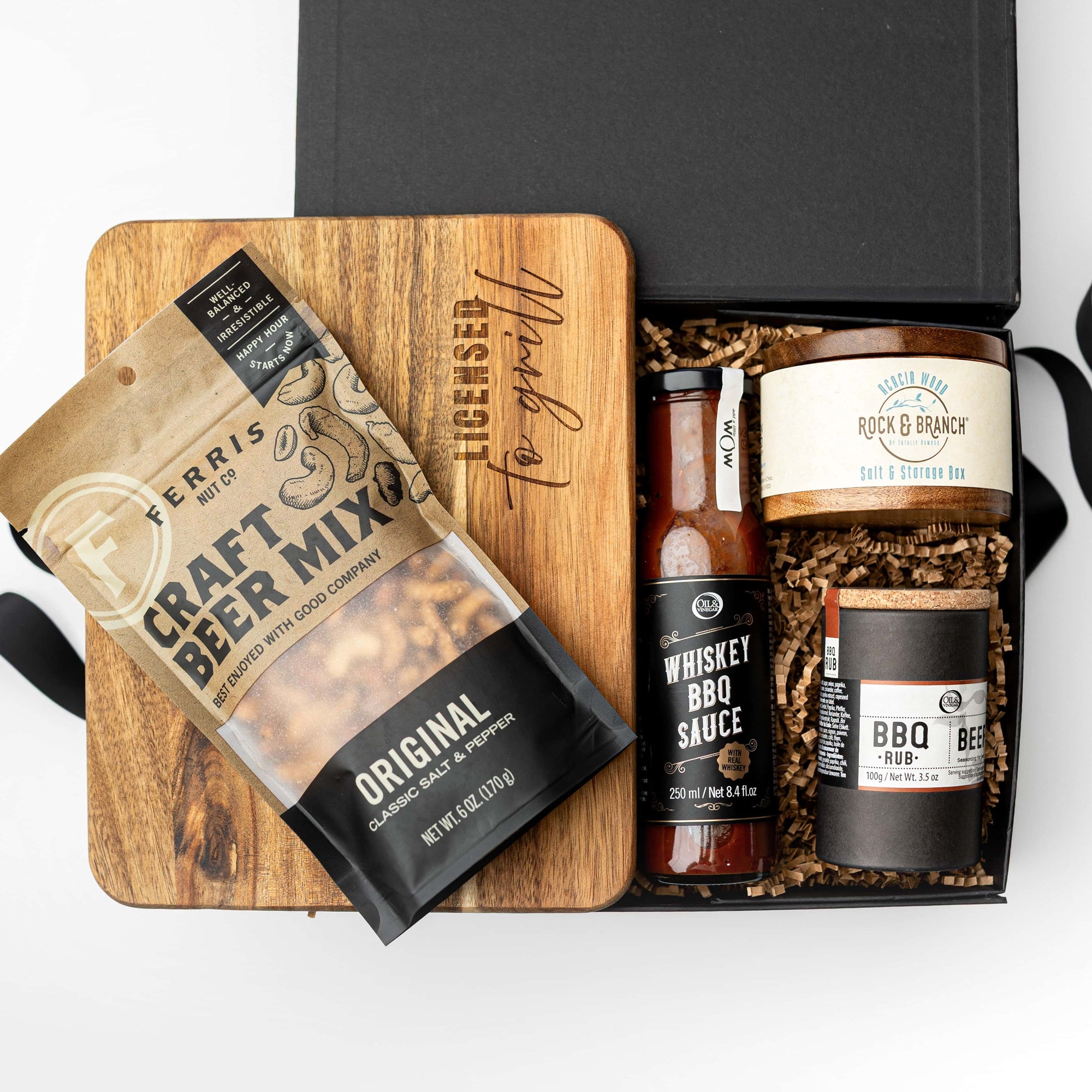 Gift set with beer mix, barbecue sauce, and jerky in a black box on a white background