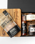 Gift set with beer mix, barbecue sauce, and jerky in a black box on a white background