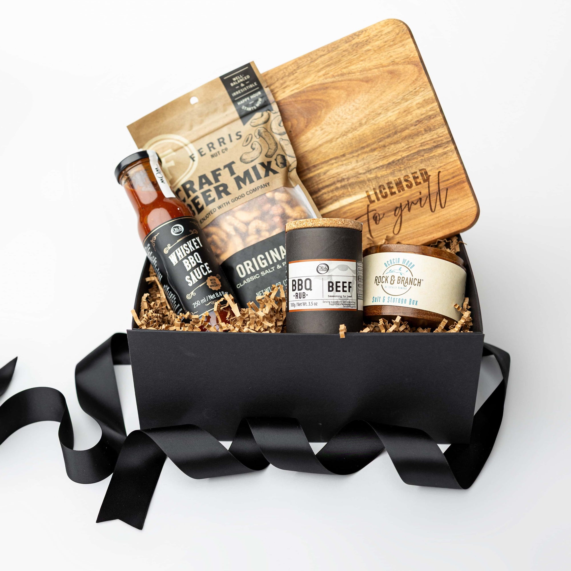 Gift basket with beer-themed items including bottles and a wooden board on a white background