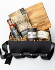 Gift basket with beer-themed items including bottles and a wooden board on a white background