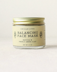 Balancing face mask jar with gold lid on a light background