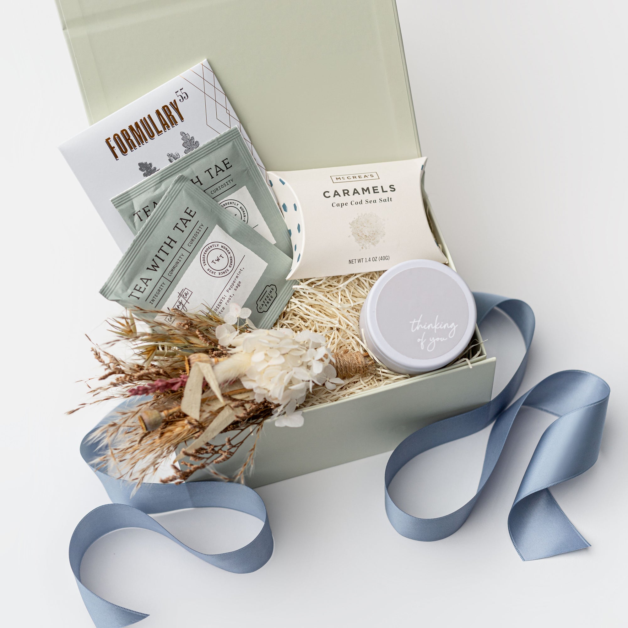 Gift box with tea packages, a jar, and decorative elements on a light background