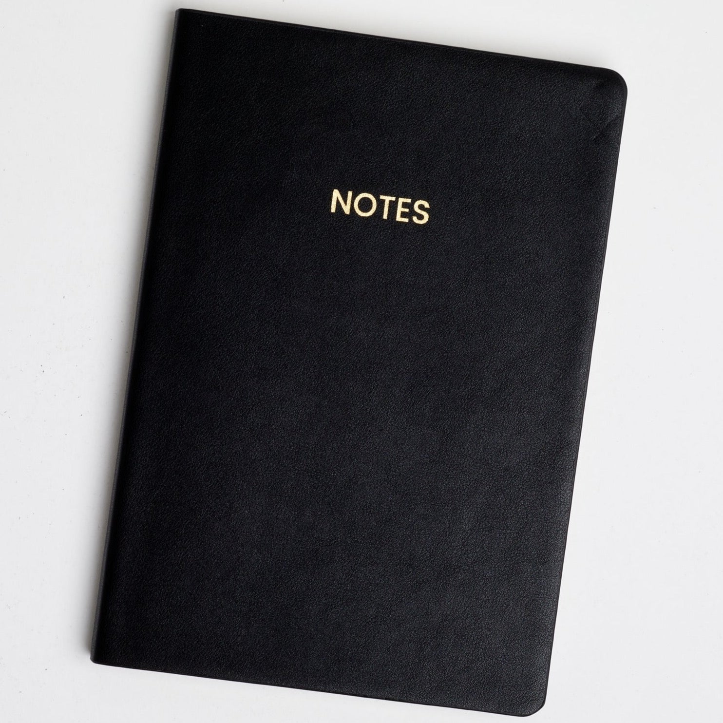 Black medium softcover notebook is featured with notes embossed in gold foil on a white background.  
