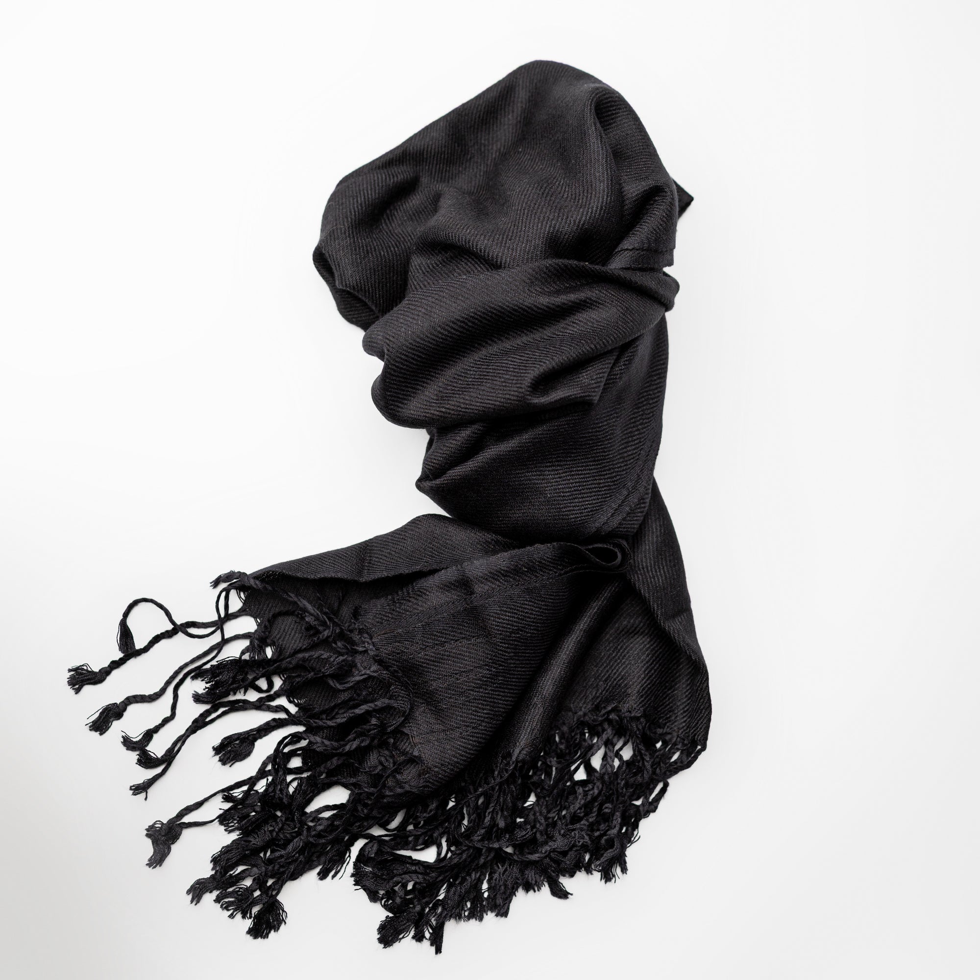 Black pashmina with fringed edges on a white background.
