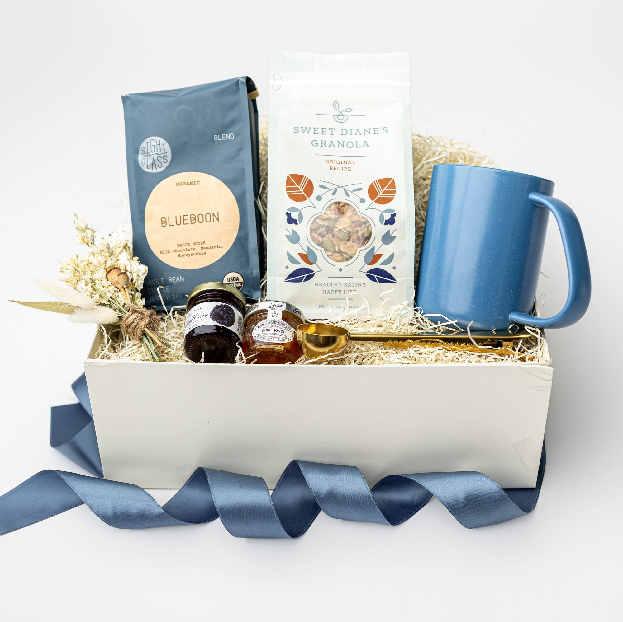 Gift basket with a blue mug, tea bags, and other items on a white background