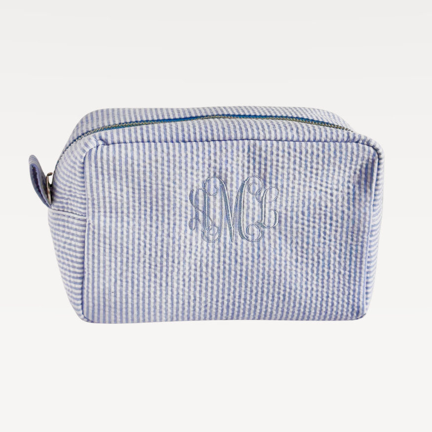 Rectangular cosmetic makeup bag with blue and white horizontal stripes and a top zipper closure.