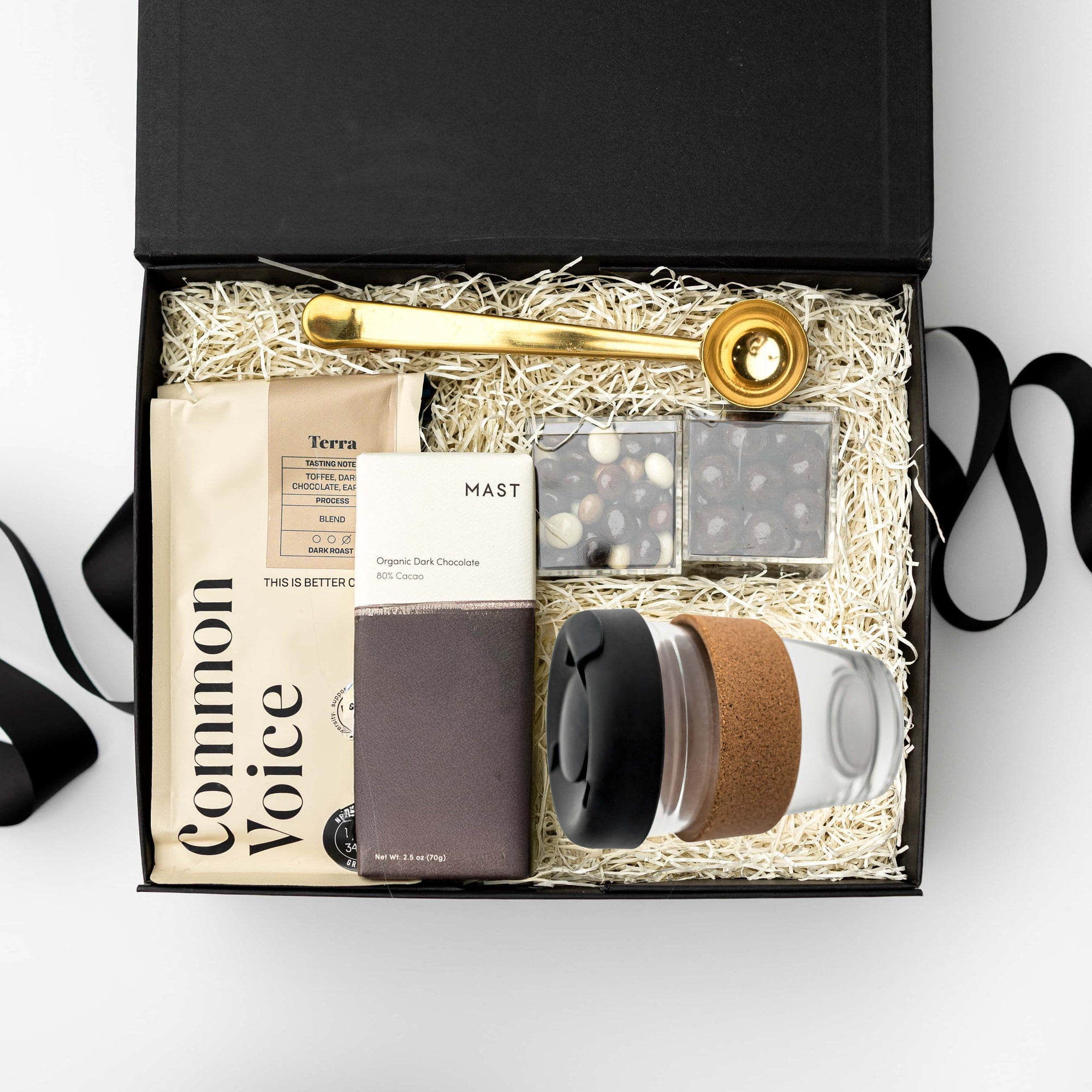Gift box with coffee mug, chocolate, and other items on a white background