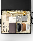Gift box with coffee mug, chocolate, and other items on a white background