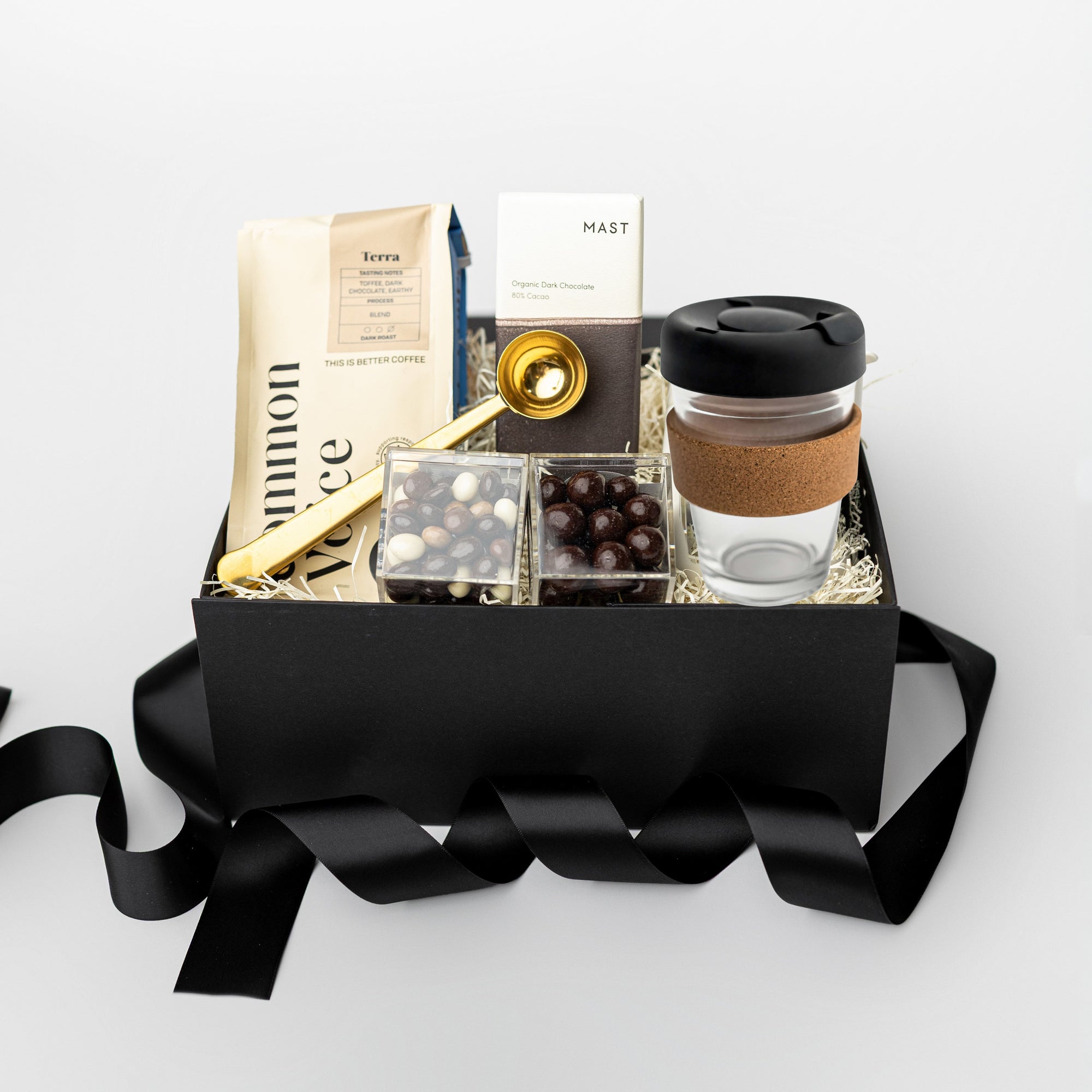 Gift box with coffee-themed items including a coffee cup, coffee beans, and a book on a white background.